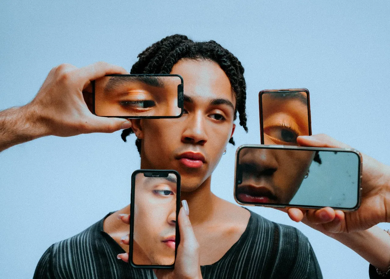 A man framed by phones held up to his face, each showing a different detail